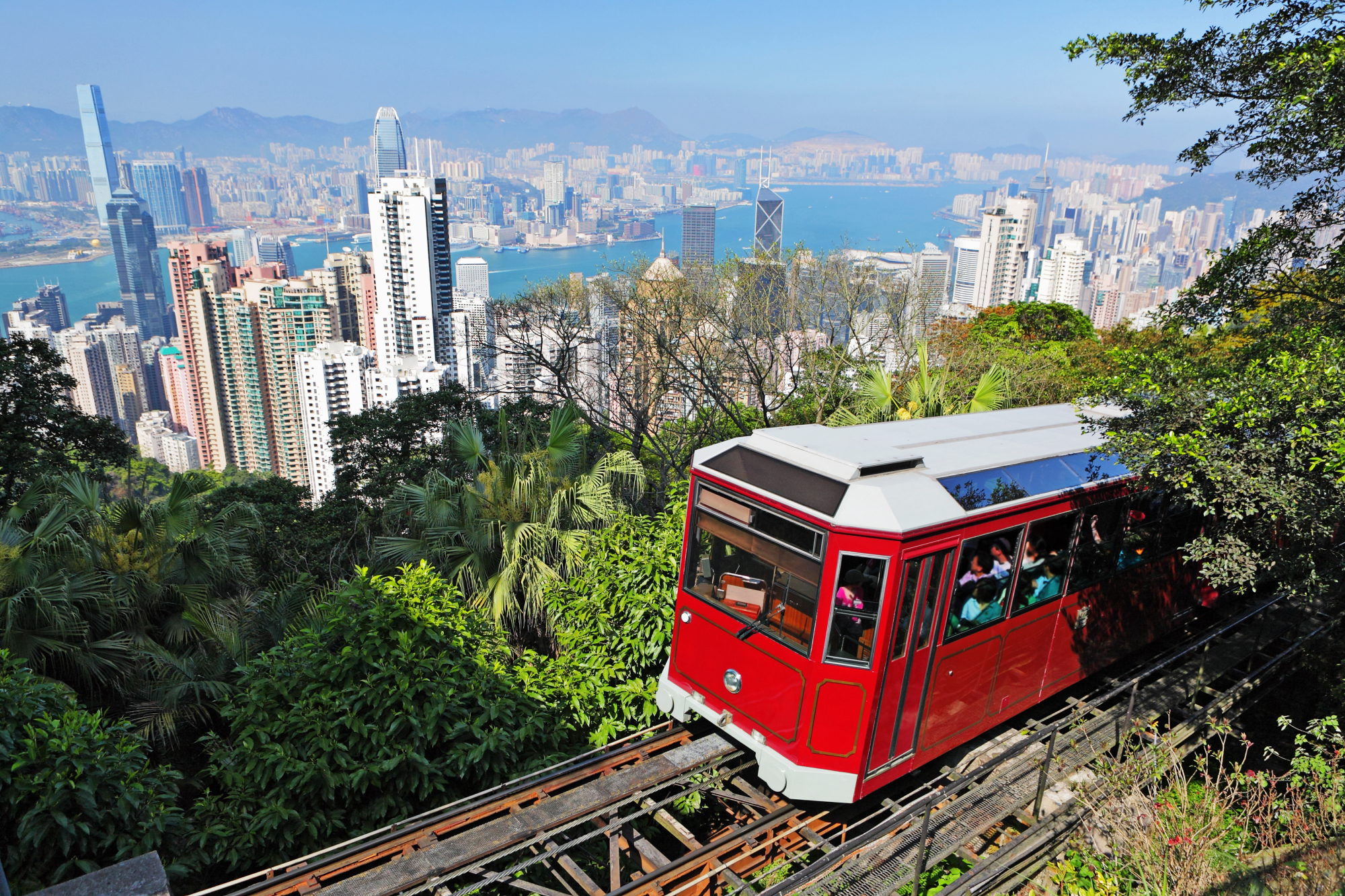 Image 3.jpg 红色的香港山顶缆车正沿著轨道上山,背景是维多利亚港和港九两岸的高楼景色。