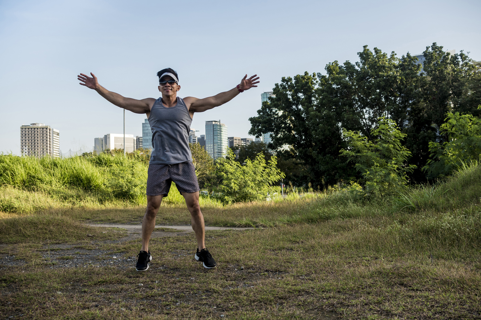iStock-1367630296.jpg A man doing jumping jacks outdoors for a full-body warm-up, jumping with arms and legs spreading to quickly raise heart rate