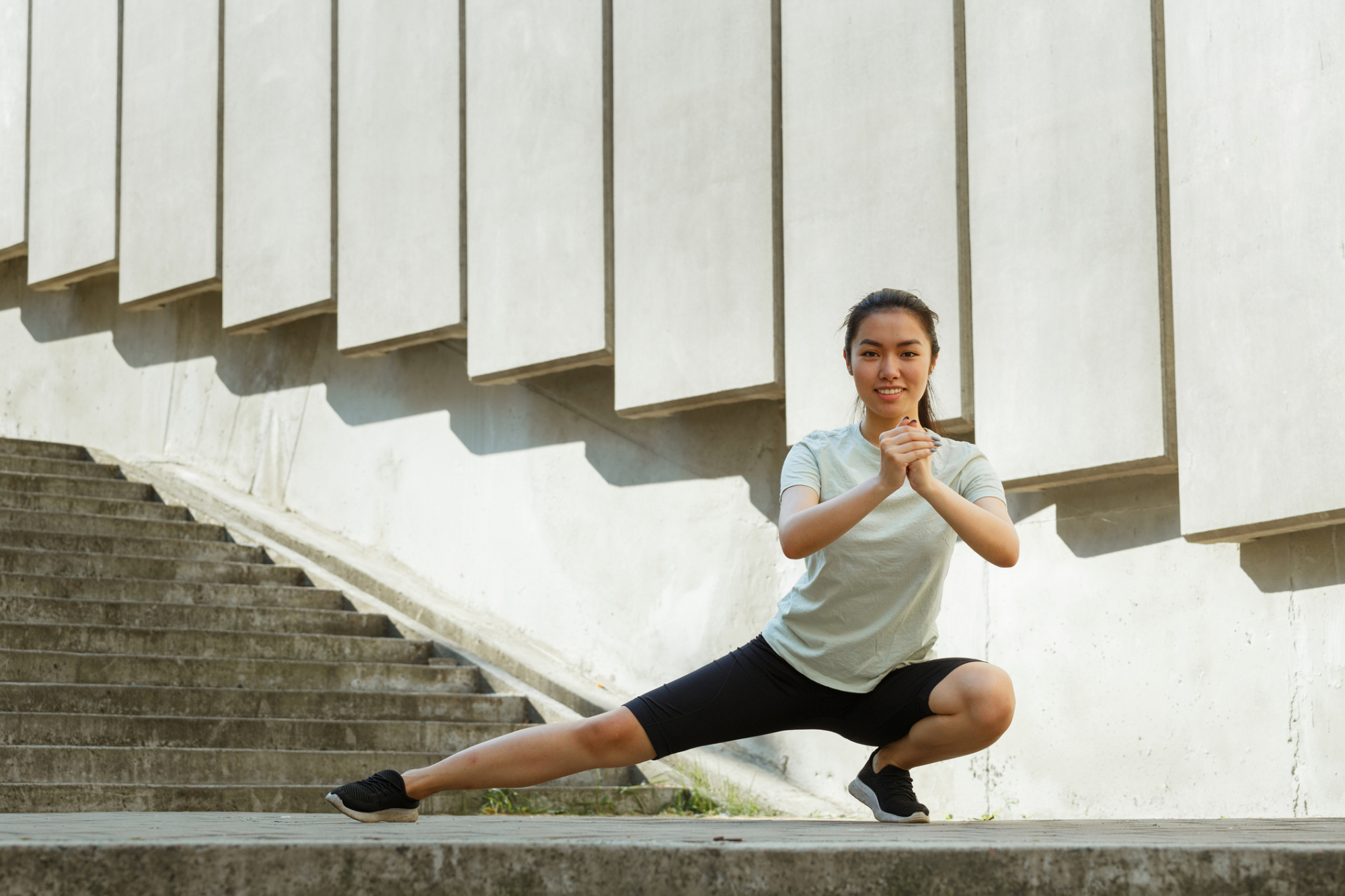 iStock-1345500635.jpg Woman demonstrating lateral lunge warm-up move, shifting weight to one side and squatting to stretch inner thigh adductor muscles.